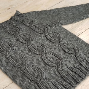 May include: A gray knitted sweater with a cable knit pattern.