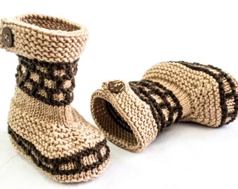 May include: A pair of knitted beige and brown booties with a button detail. The booties are made of a soft, warm yarn and have a comfortable fit.