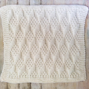 May include: A white knitted blanket with a diamond pattern.