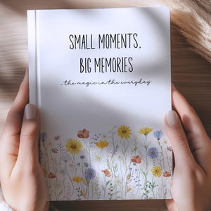 May include: A white notebook with the text "SMALL MOMENTS, BIG MEMORIES" and "the magic in the everyday" printed in black. The bottom of the cover features a colorful illustration of various wildflowers in shades of yellow, blue, and red.