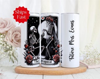 May include: Two white stainless steel tumblers with a black and white illustration of skeletons getting married. One tumbler says "The Proposal" and the other says "Future Mrs. Evans".