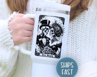 May include: White insulated tumbler featuring a black and white illustration of two skeletons in formal attire, a top hat and a veil, with the words "Till Death". The tumbler has a white handle and a silver rim.