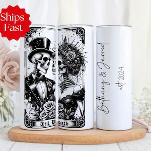 May include: Two white stainless steel tumblers with black designs. One tumbler features a black and white illustration of a skeleton couple with the text "Till Death". The other tumbler has the text "Bethany & Jarrod est. 2024".