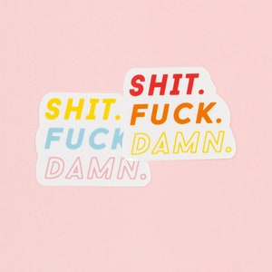 Peut inclure: Deux autocollants blancs avec les mots "SHIT. FUCK. DAMN." en différentes couleurs. Les mots sont empilés les uns sur les autres, avec "SHIT." en jaune, "FUCK." en orange, "DAMN." en rose et "FUCK." en bleu.