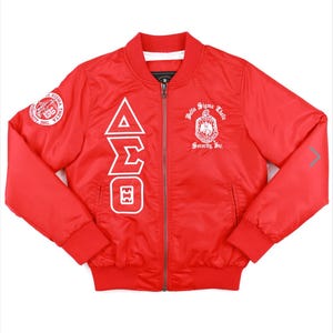 May include: Red bomber jacket with white lettering. The lettering says "Delta Sigma Theta Sorority, Inc." and features the Greek letters "ΔΣΘ".