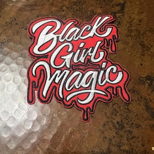 May include: Red and white embroidered patch with the text "Black Girl Magic" in a dripping font style.