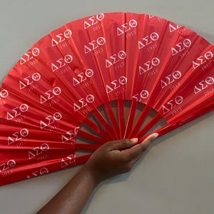 May include: A red folding fan with white lettering that says "ΔΣΘ 1913" repeated across the surface.