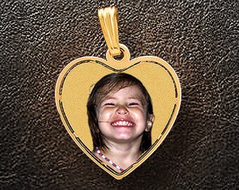 May include: A gold heart-shaped pendant with a photo of a smiling young girl inside.