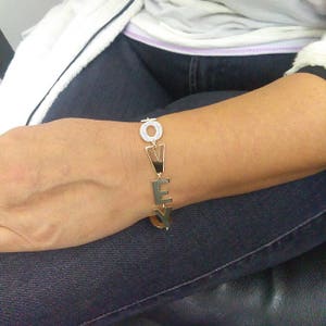 Puede incluir: Pulsera de oro con la palabra "LOVE" escrita en letras grandes. Cada letra est&aacute; decorada con peque&ntilde;as piedras transparentes.