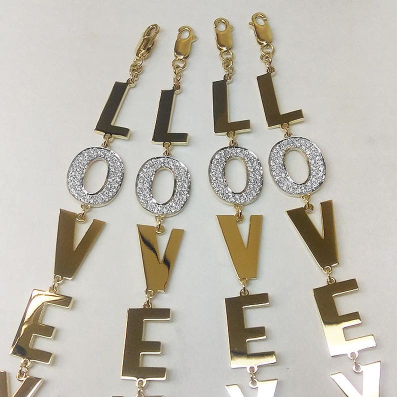 Puede incluir: Cuatro pulseras de charms 'LOVE' en tono dorado con charms 'O' incrustados de cristales.