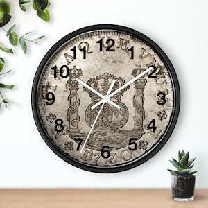 May include: A round wall clock with a black frame. The clock face features a detailed, antique coin design with Roman numerals and ornate details. The clock hands are white, and the overall aesthetic is vintage.
