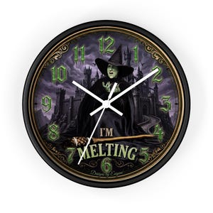 May include: A round wall clock with a black frame featuring a green-skinned witch in a black hat and cloak standing before a dark castle. The clock face displays green numbers, white hands, and the text I'M MELTING with a broomstick graphic.