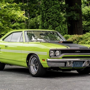 May include: A lime green 1970 Plymouth GTX muscle car with black racing stripes and a black hood. The car has a chrome bumper and a license plate that reads "1970".