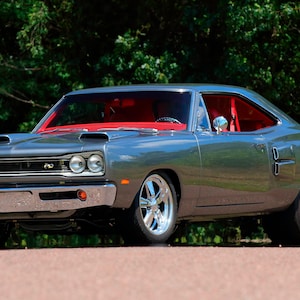 May include: A gray 1969 Dodge Super Bee muscle car with red interior and a black stripe on the side. The car has a custom hood with two air scoops and chrome bumpers.