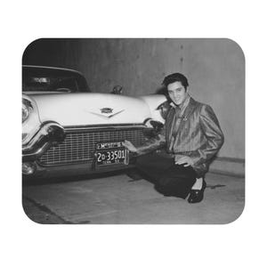 Puede incluir: Una fotografía en blanco y negro de un hombre posando junto a un Cadillac blanco. El coche tiene una matrícula que dice "Memphis 1957" y "20-33501" con "Tenn. 56" debajo.