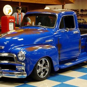 May include: A blue 1950s Chevrolet pickup truck with rust on the body and chrome accents. The truck is parked on a checkered floor.