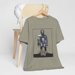 May include: A green t-shirt with a black and white graphic of a man with a mask and the text "The Wicker Man".