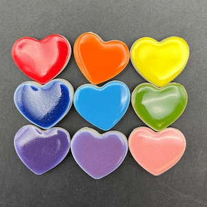 May include: Nine ceramic heart-shaped tiles in a rainbow color pattern. The tiles are arranged in three rows of three, with the red tile at the top left and the pink tile at the bottom right.