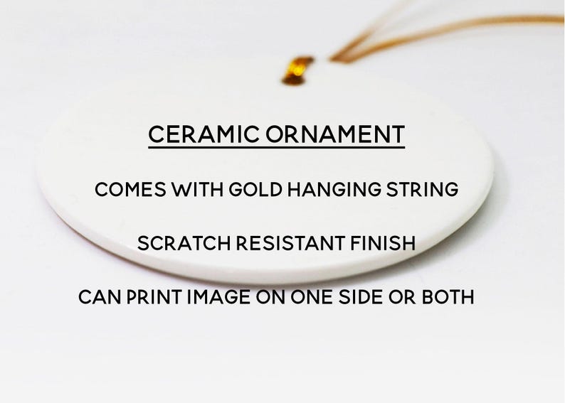 May include: A white oval ceramic ornament with a gold hanging string. The text on the ornament reads: CERAMIC ORNAMENT, COMES WITH GOLD HANGING STRING, SCRATCH RESISTANT FINISH, CAN PRINT IMAGE ON ONE SIDE OR BOTH. The surface has a smooth finish.