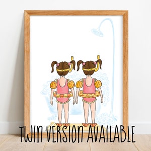 May include: Watercolor illustration of two girls in pink swimsuits, yellow arm floaties, and swim rings, standing in a bathtub under a shower. The artwork is framed in a light brown wooden frame. Text at the bottom reads "TWIN VERSION AVAILABLE".