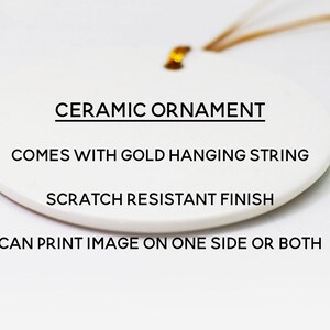 May include: A white ceramic ornament with a gold hanging string. The text on the ornament reads: "CERAMIC ORNAMENT", "COMES WITH GOLD HANGING STRING", "SCRATCH RESISTANT FINISH", and "CAN PRINT IMAGE ON ONE SIDE OR BOTH".