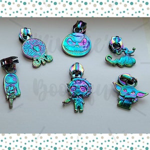 May include: Six iridescent zipper pulls with different character designs. The designs include a skull, a girl with long hair, a zombie, a baby, and a creature with large ears.