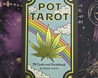 May include: A black tarot card box with the words "POT TAROT" in gold lettering. The box features a rainbow, clouds, and a large green cannabis leaf. The box also states "78 Cards and Guidebook" and "BY PEGGY WHITE".