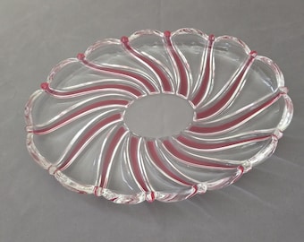 Könnte beinhalten: Klarer Glas-Servierteller mit gewelltem Rand und einer zentralen Öffnung. Das Gericht hat ein Spiraldesign mit abwechselnd klaren und roten Streifen. Der Rand hat kleine rote Akzente.