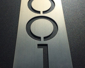 May include: A silver metal house number plaque with the number 2001 cut out. The plaque has two small holes on either side.