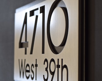 May include: A silver metal house number sign with black numbers and text. The sign reads "4710 West 39th".