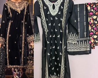 Op de afbeelding: Zwart geborduurde tuniek en broek. De tuniek heeft ingewikkelde gouden borduursels rond de halslijn, mouwen en zoom. De broek heeft een bloemenpatroon. De outfit wordt op een hanger getoond.
