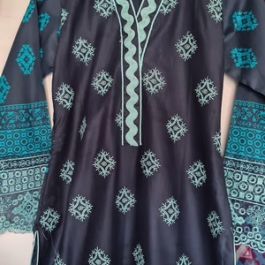 May include: A dark blue tunic with a teal embroidered neckline and geometric patterns. The tunic has long sleeves with a teal embroidered border and a teal embroidered hem.