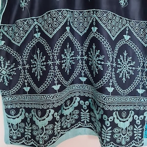 May include: A black and teal embroidered fabric with a geometric pattern. The fabric has a scalloped edge.