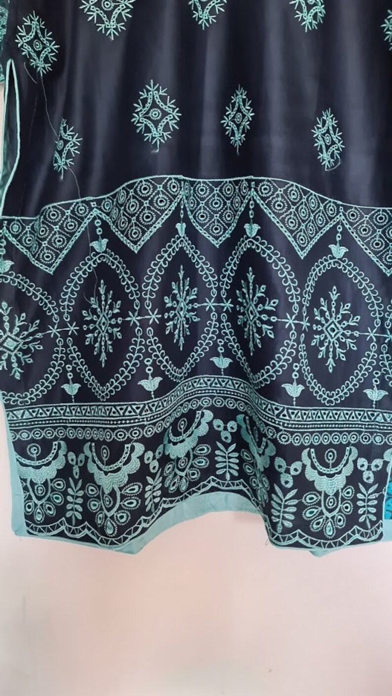 May include: A black and teal embroidered fabric with a geometric pattern. The fabric has a scalloped edge.