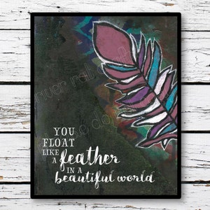 Puede incluir: Impresión artística enmarcada con una pluma estilizada en tonos morados, turquesa y blanco sobre un fondo oscuro. La obra incluye el texto blanco "You float like a feather in a beautiful world".