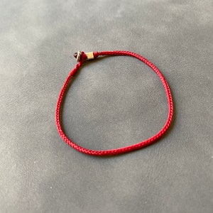 May include: A red string bracelet with a silver bead.