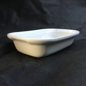 Peut inclure: Plat à four rectangulaire blanc avec un bord surélevé et le logo Le Creuset.