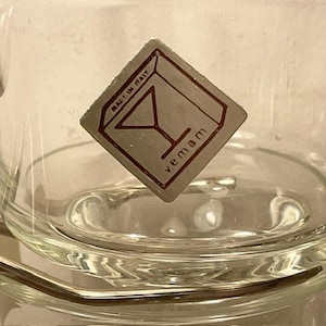 May include: A clear glass cup with a silver square label that says "vemam" and "Made in Italy" with a martini glass icon.