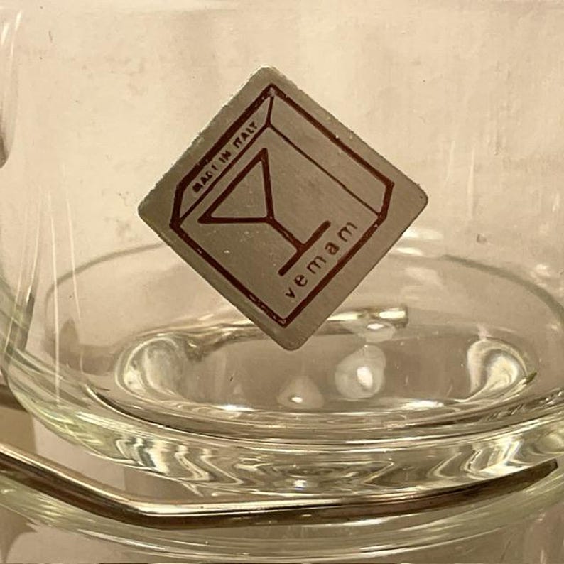 May include: A clear glass cup with a silver square label that says "vemam" and "Made in Italy" with a martini glass icon.