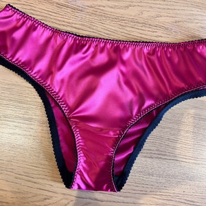 May include: A pair of pink satin underwear with black lace trim.
