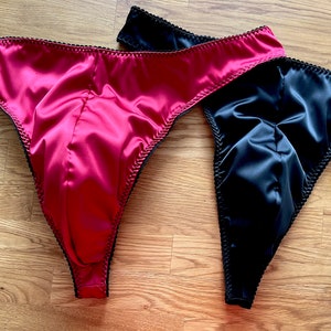 May include: Two pairs of satin underwear, one black and one pink, with black trim.