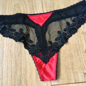 May include: Black lace and red satin thong underwear with floral embroidery.