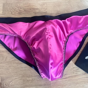 May include: Pink satin underwear with black trim and a satin finish.