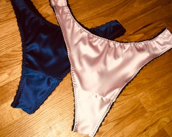May include: Two pairs of satin underwear with black lace trim. One pair is navy blue and the other is pink.