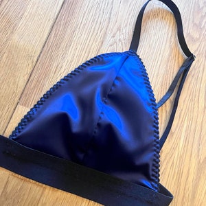May include: A dark blue satin triangle bra with black adjustable straps and a black elastic band.