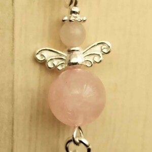 Puede incluir: Un brazalete de plata con una cuenta de cuarzo rosa y un dije de &aacute;ngel de plata.