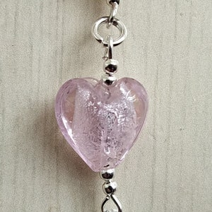 Puede incluir: Una cuenta de vidrio rosa en forma de coraz&oacute;n con cuentas de metal plateado y una cadena de metal plateado.