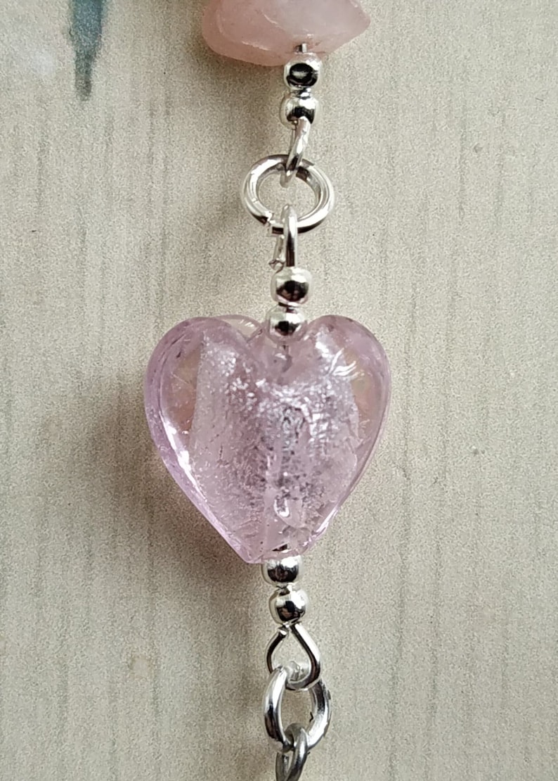 Puede incluir: Una cuenta de vidrio rosa en forma de coraz&oacute;n con cuentas de metal plateado y una cadena de metal plateado.