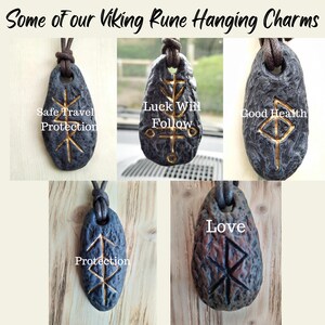 May include: Five Viking rune pendants on black leather cords. The runes are inscribed on grey and brown stone-like charms. The runes are inscribed in gold paint. The charms are labeled with the following words: Safe Travel Protection, Luck Will Follow, Good Health, Protection, Love.