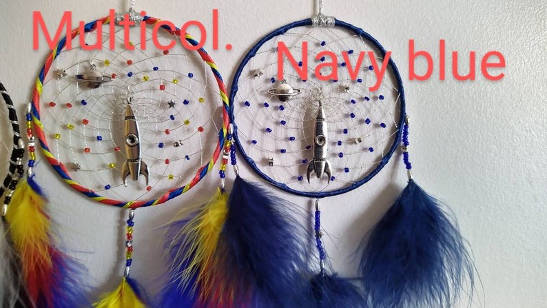 Pu&ograve; includere: Due acchiappasogni con un ciondolo a forma di razzo e pianeta che pendono da essi. Un acchiappasogni ha un anello esterno blu, rosso e giallo, l'altro ha un anello esterno blu navy. Entrambi gli acchiappasogni hanno piume blu e bianche.